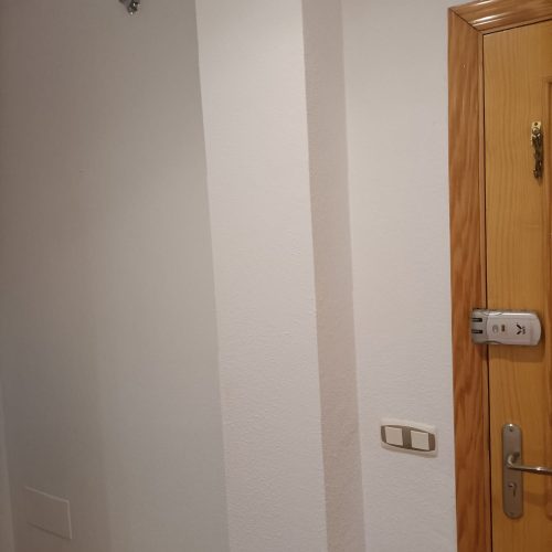 Recibidor de una casa renovada con una mano de pintura blanca